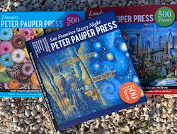 Three puzzle boxes, with San Francisco Starry Night on op of Donuts and London