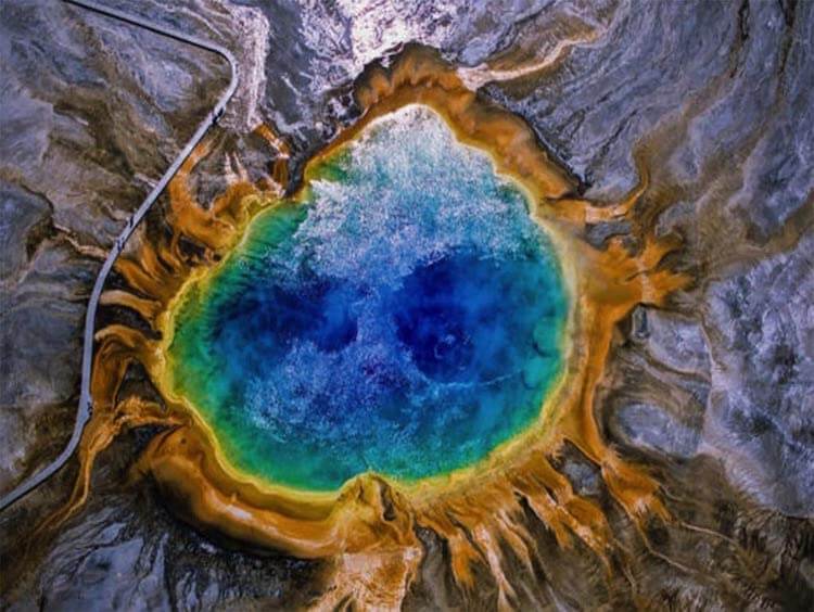 Bright blue water of the spring in the center fading to green on the outside, with a brown ring of the land fading into brown .