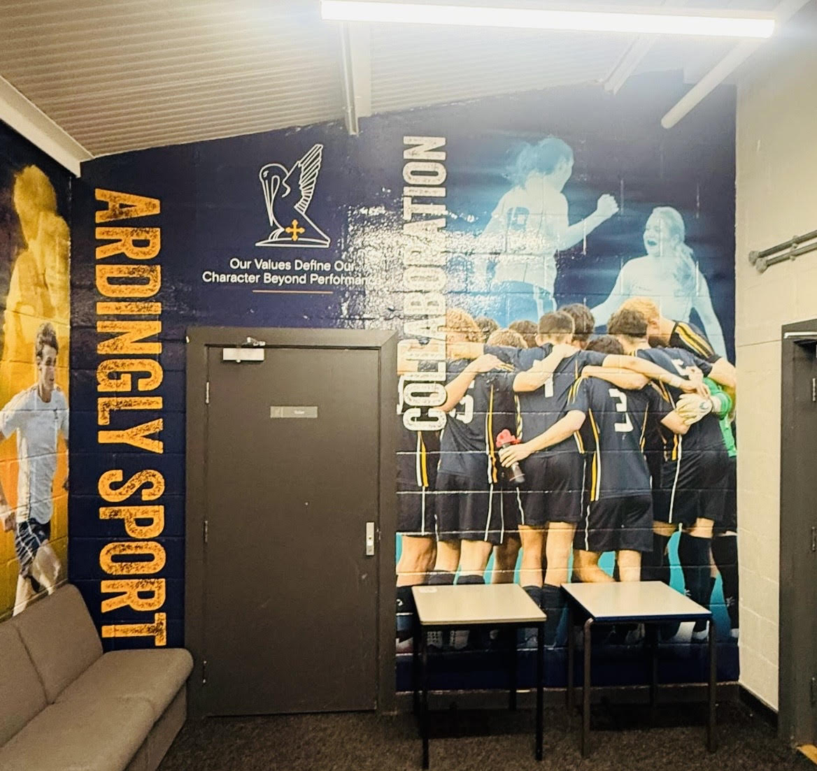 Ardingly Sport wall graphic with a team huddle and the college crest at the sports hall entrance.