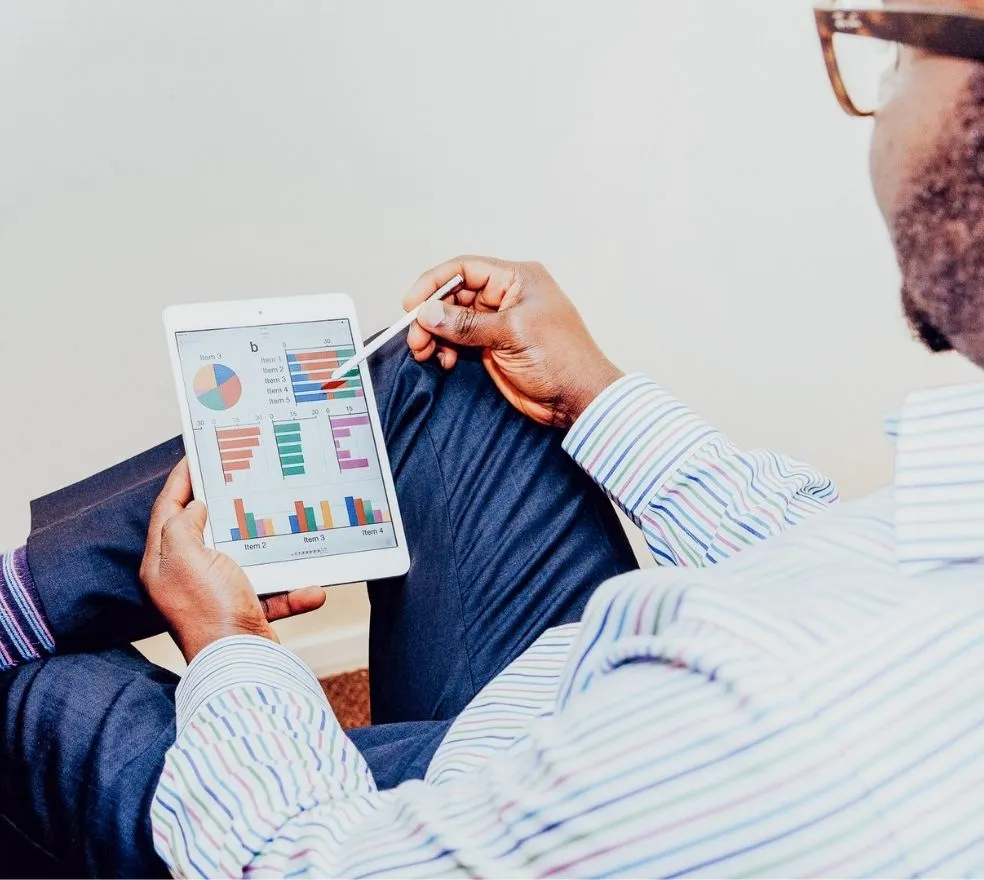 Une personne tenant une tablette avec un dashboard montrant des graphiques de données