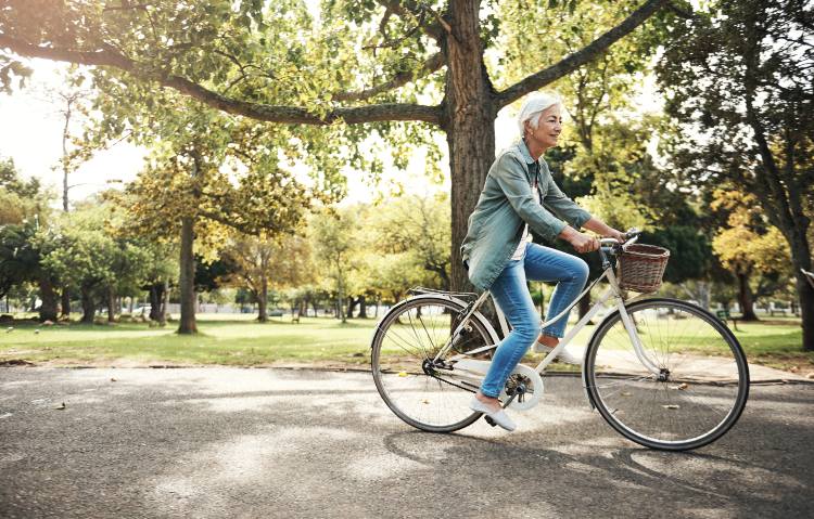 A woman riding a bicycle through a lush green park on a sunny day in Central Ohio