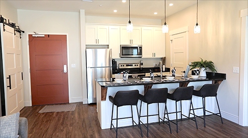A stylish, modern kitchen with a bar and stools designed for senior living in Central Ohio
