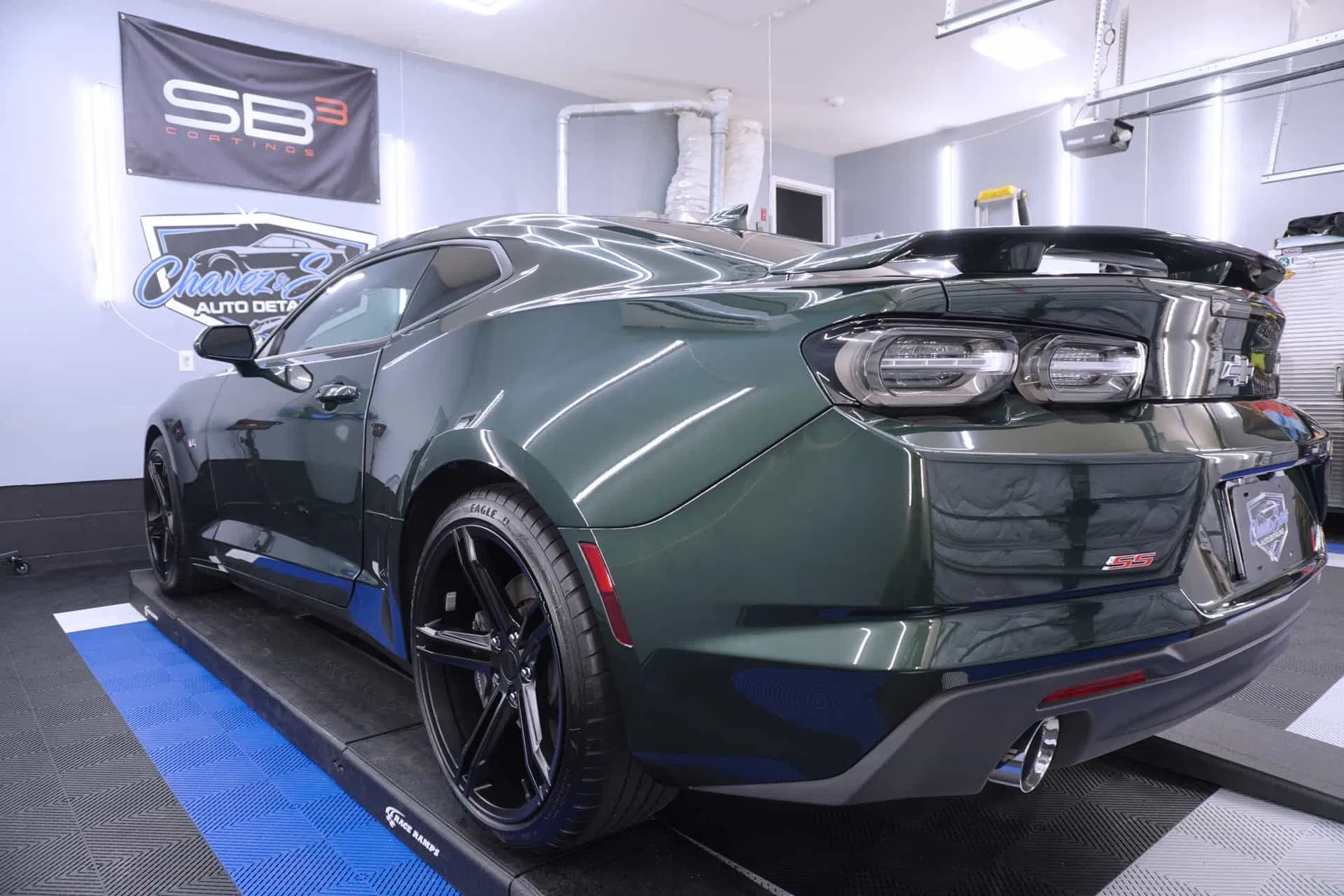 A dark green Camaro SS sits in a detailing bay, freshly treated with SB3 Trinity ceramic coating for an ultra-deep shine and advanced paint protection.
