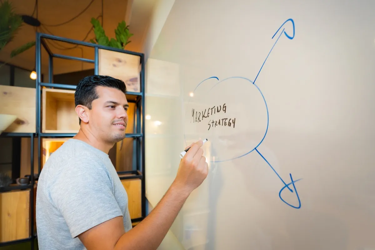 Mann vor dem Whiteboard plant Marketingstrategie