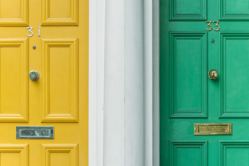A yellow front door and a green front door side-by-side, representing choices or alternative paths.