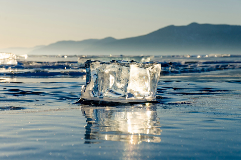 A clear block of ice slowly melting in the sunlight, symbolizing urgency, temporary conditions, and the passage of time.