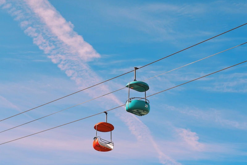 Chairlift gondolas against a blue sky, symbolizing upward progress, continuous deployment, and momentum.
