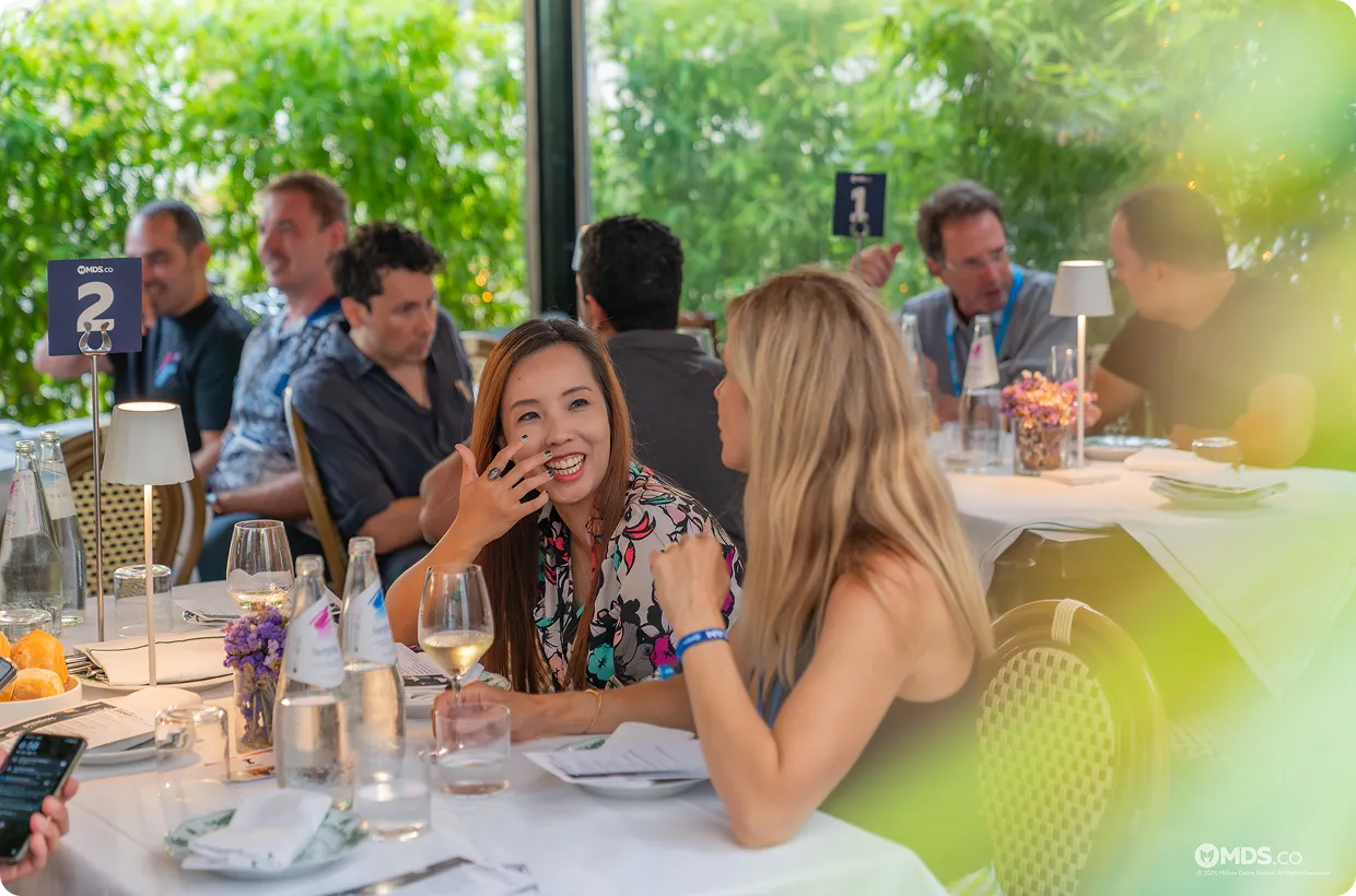 Summit attendees laughing together at a dinner table