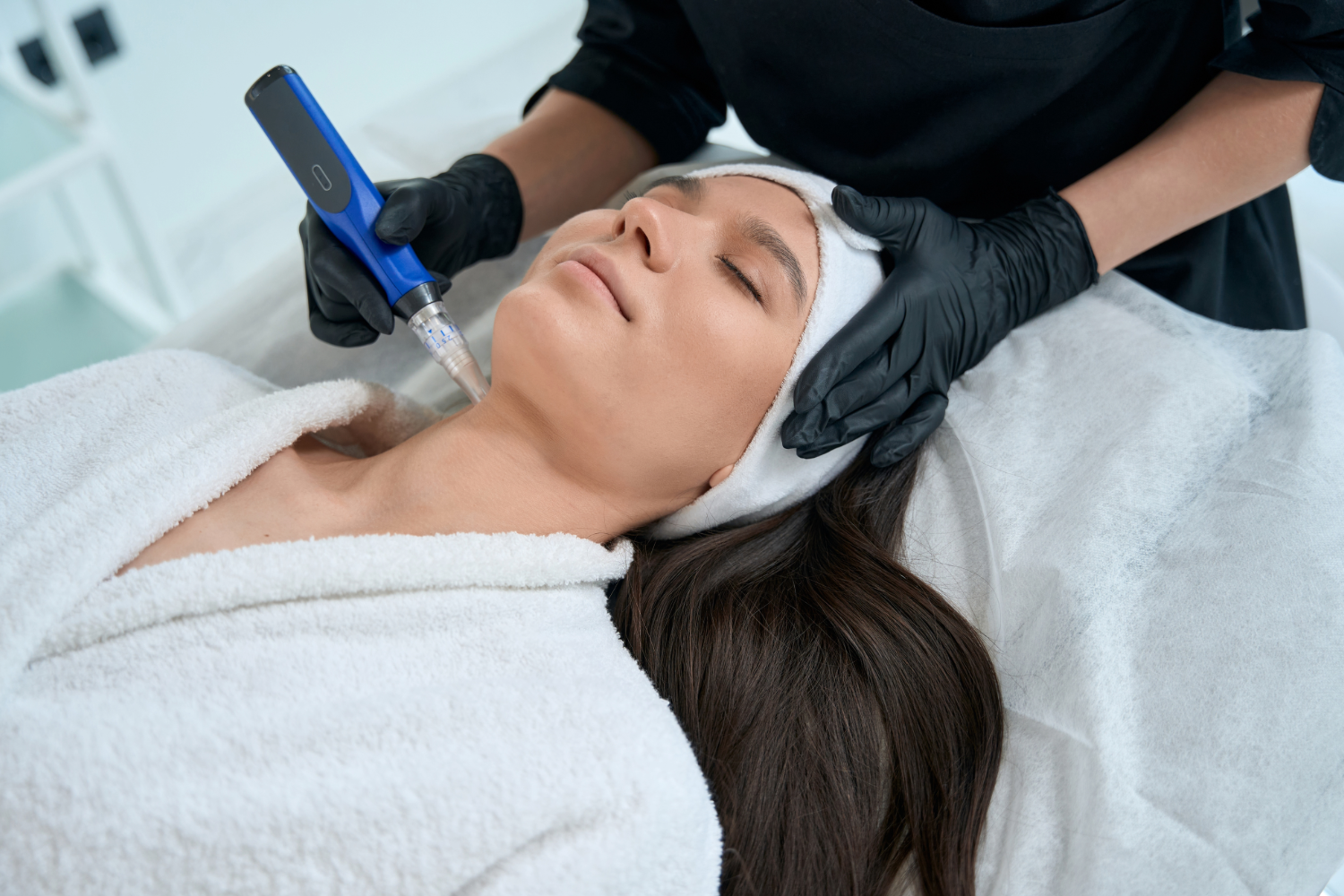 Woman receiving microneedling facial treatment.