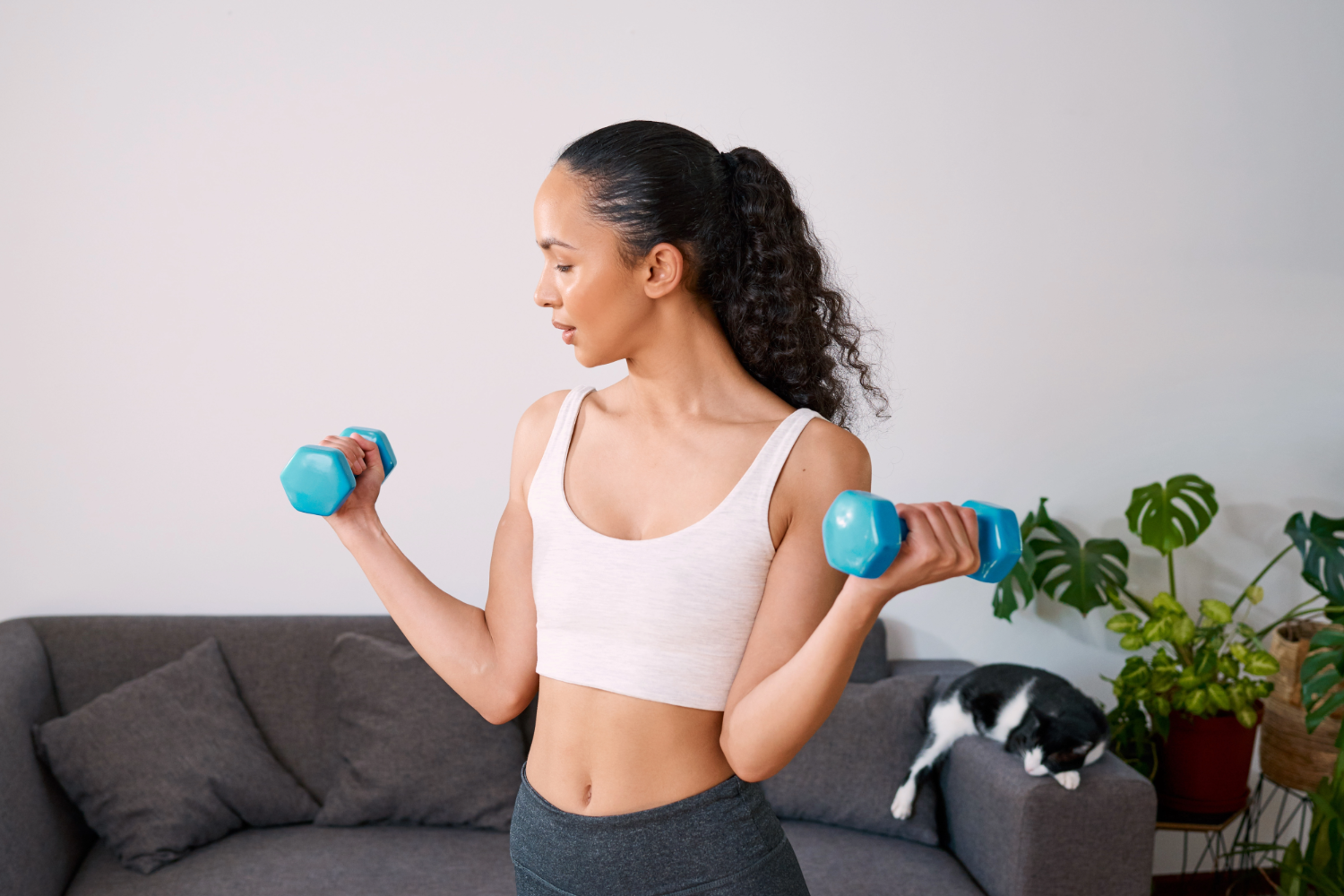 Woman lifting dumbbells in living room.