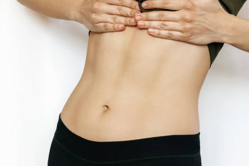 Hands touching a toned abdomen.