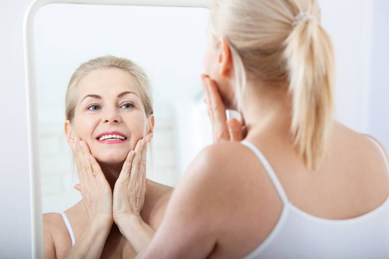 Woman smiling at her reflection in a mirror.