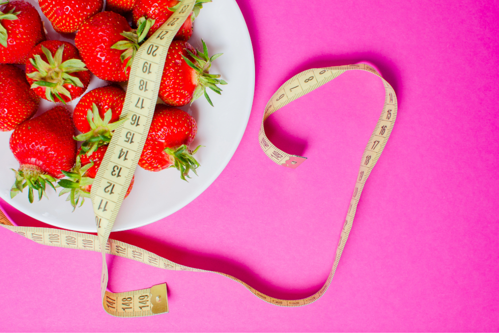 Strawberries on a plate with measuring tape.