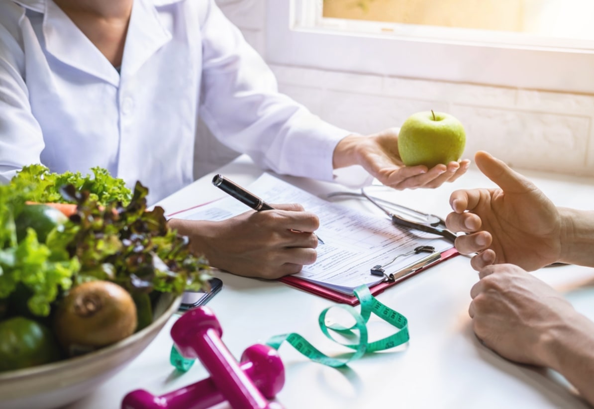 Nutritionist consulting with client, apple in hand.
