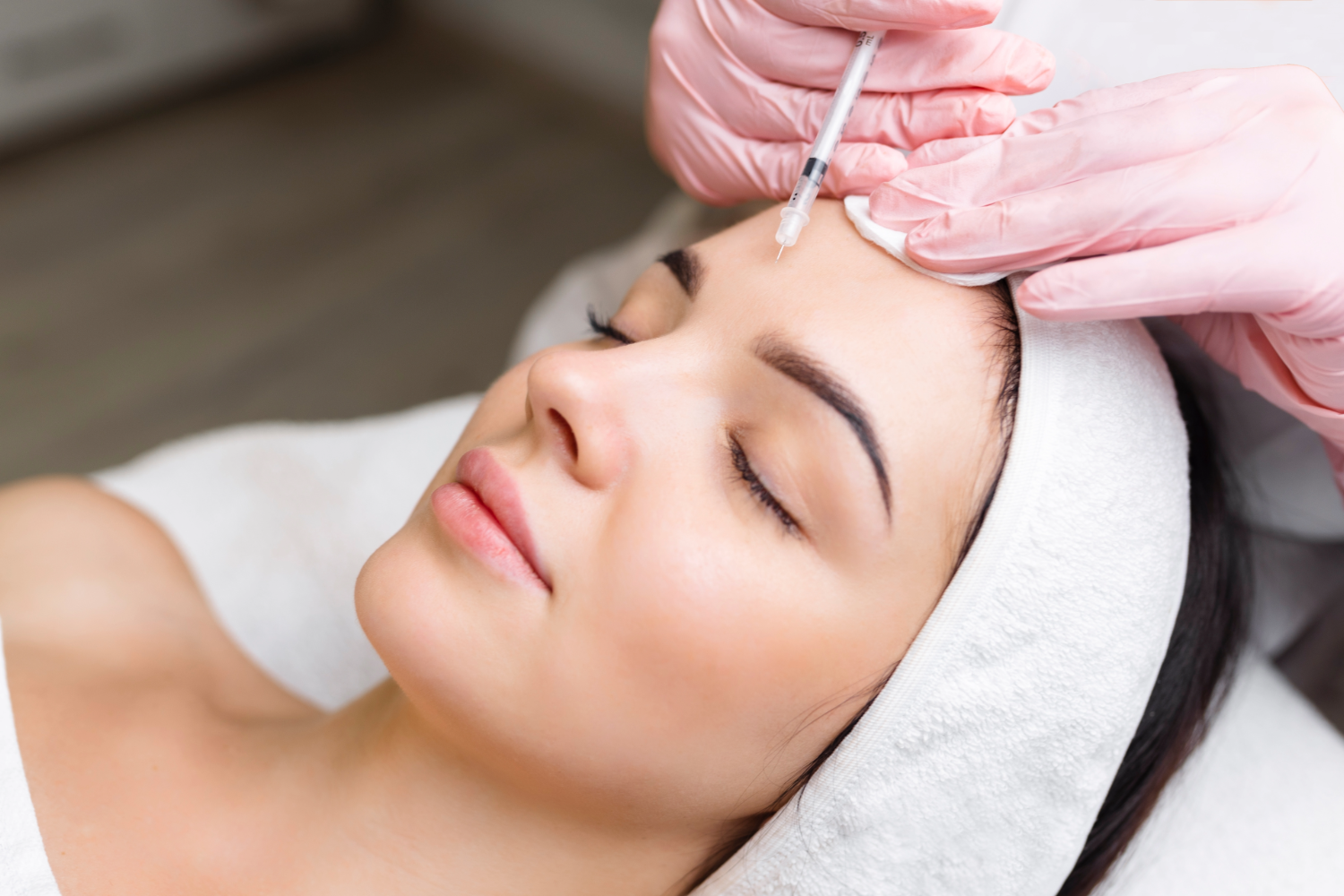 Woman receiving Botox injection on forehead.
