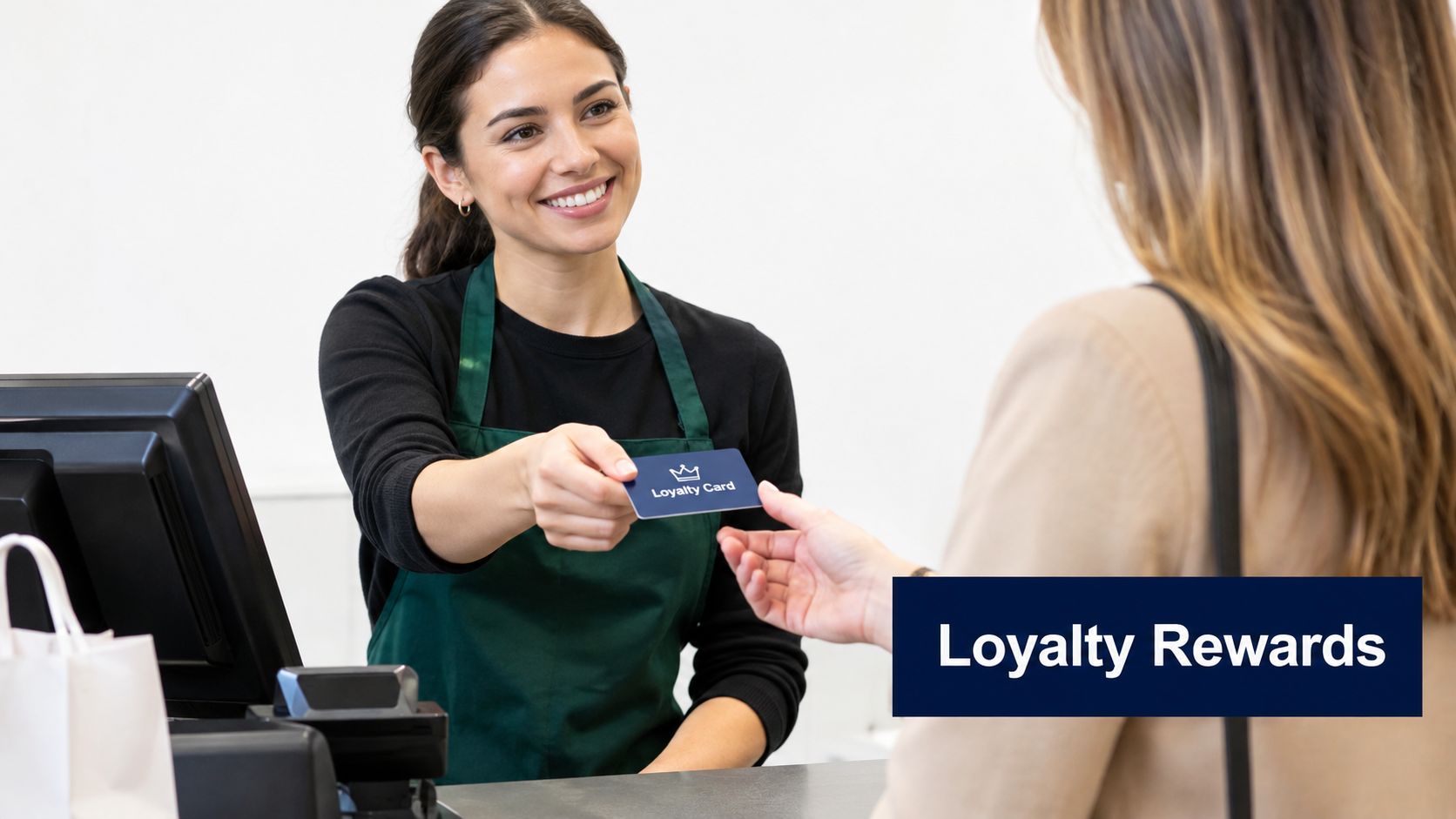 A friendly cashier smiling while handing a loyalty card to a customer at a checkout counter.