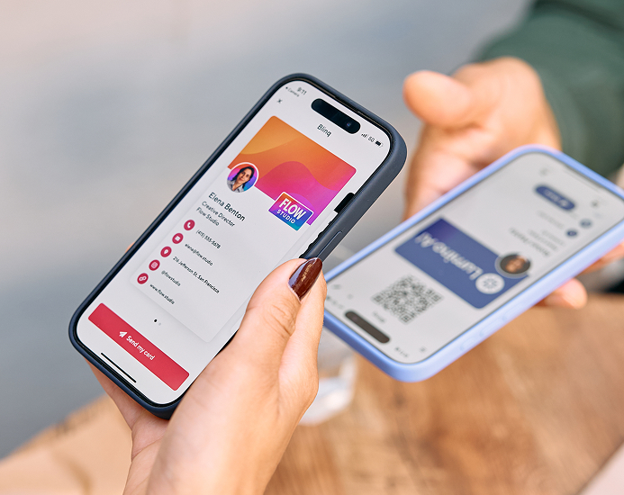 Two people exchanging digital business cards using smartphones, one displaying contact details and the other showing a QR code.