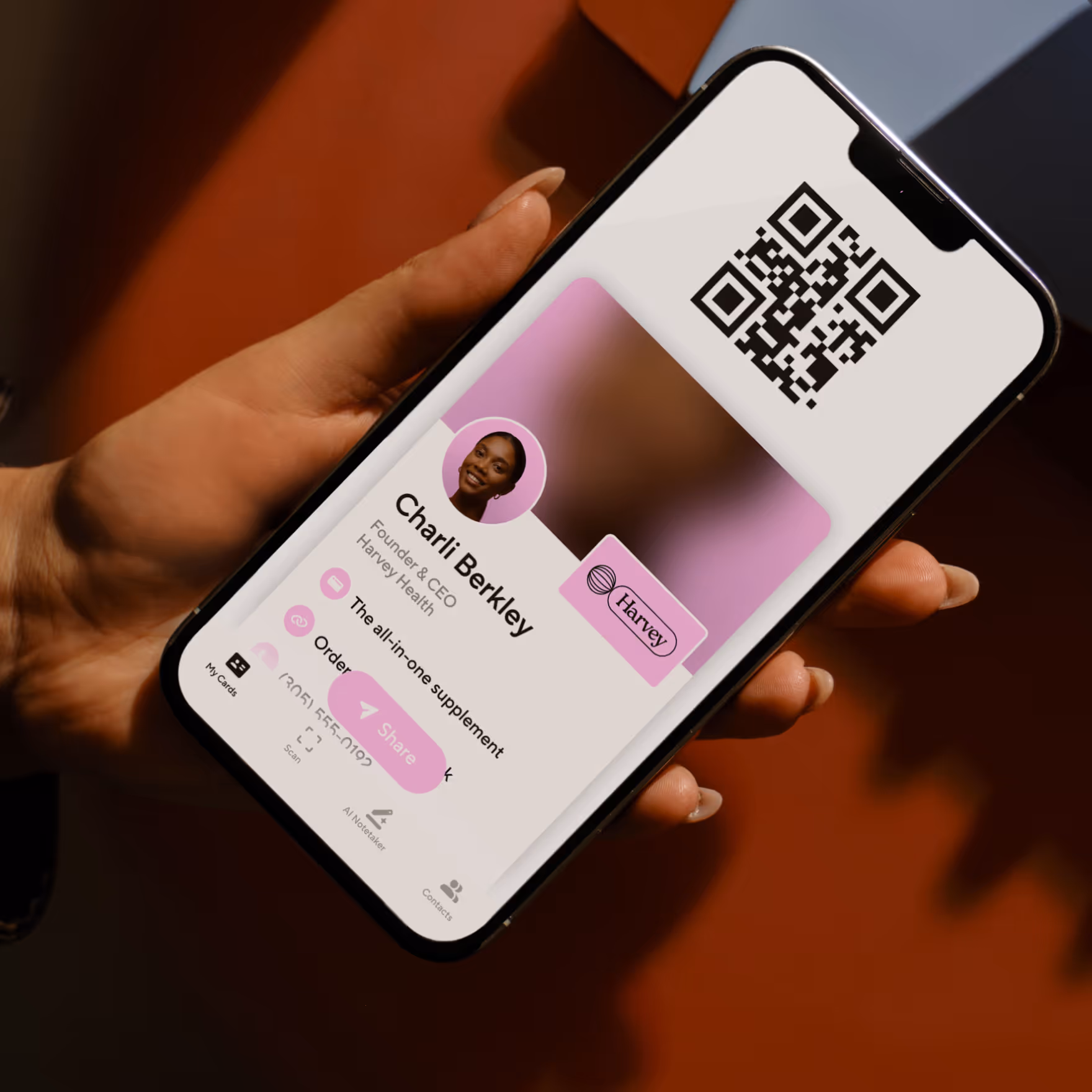 Hand holding smartphone displaying a digital business card for Olivia Grant, Founder & CEO of Blooming, with a QR code at the top.