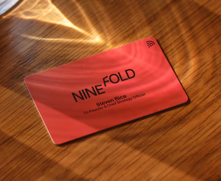 Red business card on wood surface with text: NINEFOLD and Steven Rice, Co-Founder & Chief Strategy Officer.