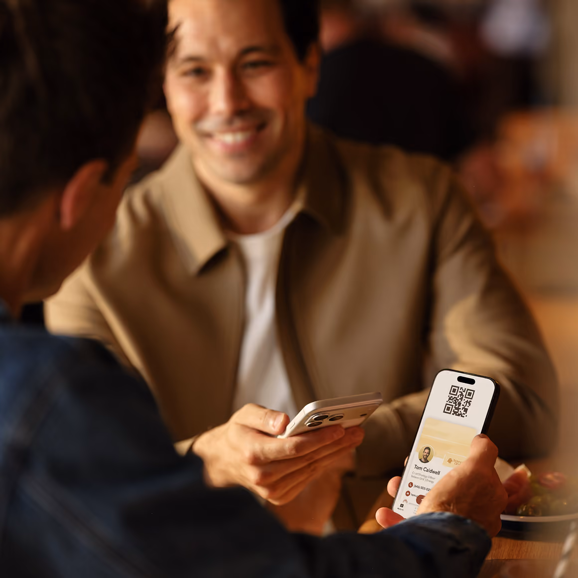 A man smiling while sharing his Blinq digital business card from his phone at an event