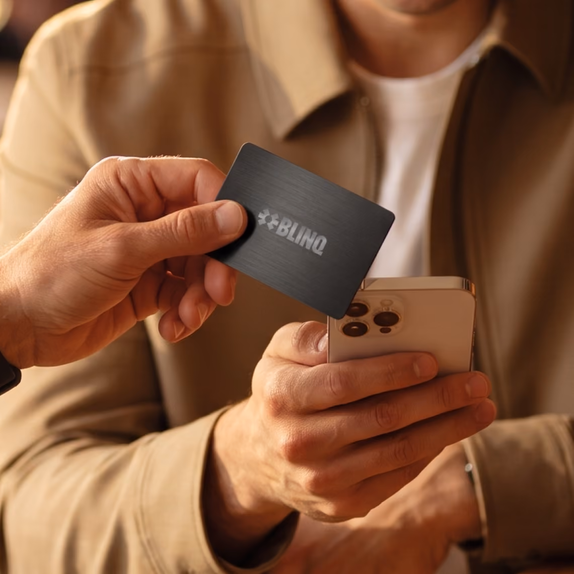 Person tapping a black Blinq NFC business card on a smartphone to share their contact details