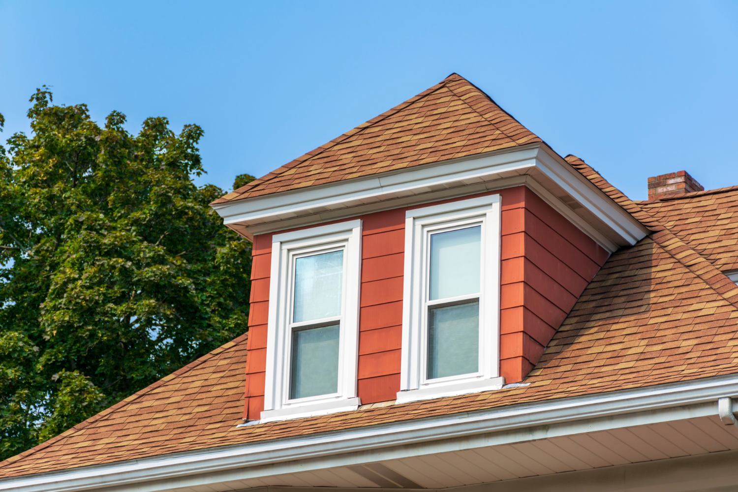 Red dormer on shingle roof with two windows.
