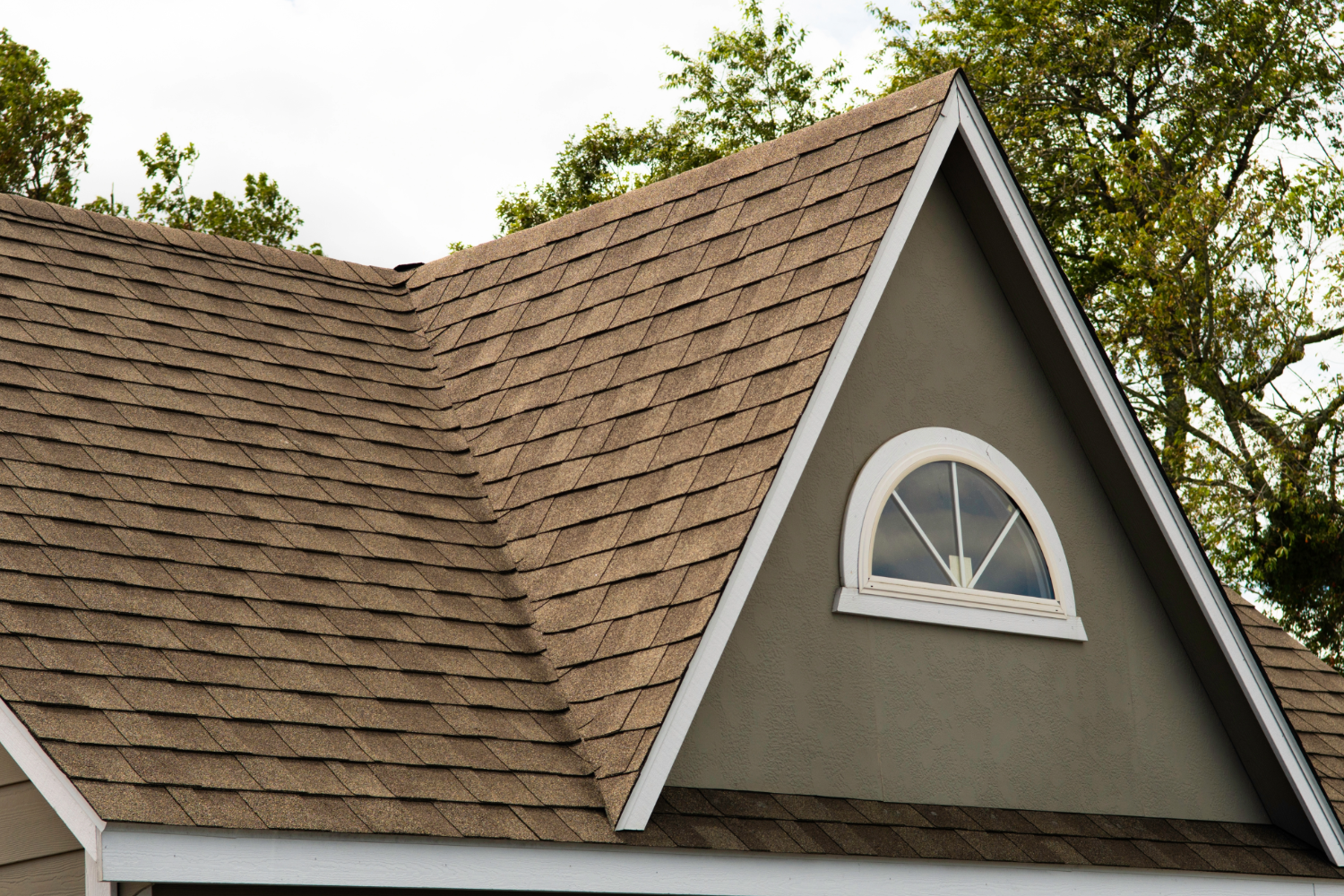 Gabled roof with brown shingles and arched window.