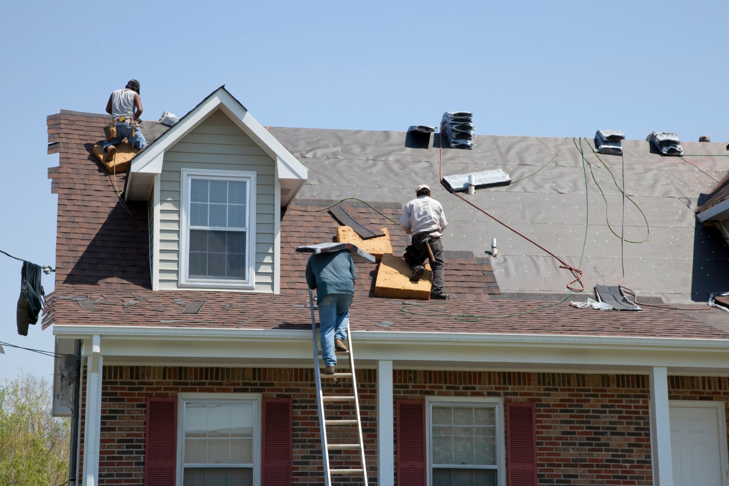 Roofers repairing shingles on house roof