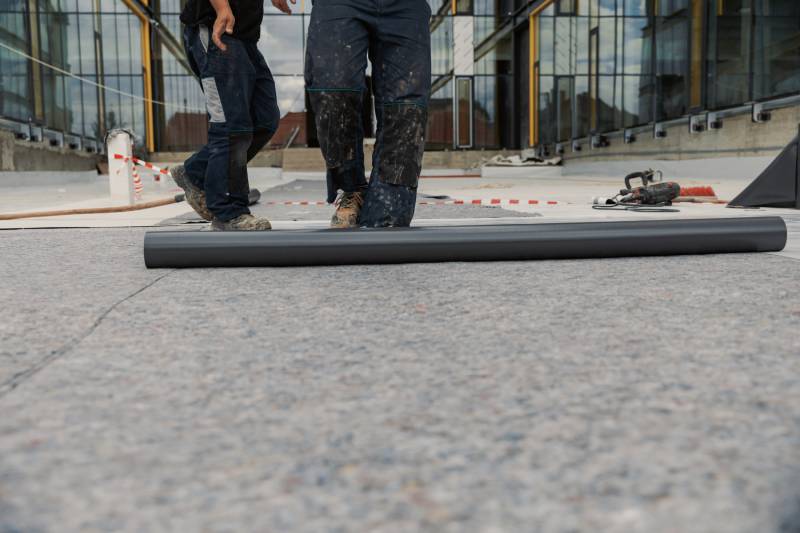 Roofers installing flat roofing.