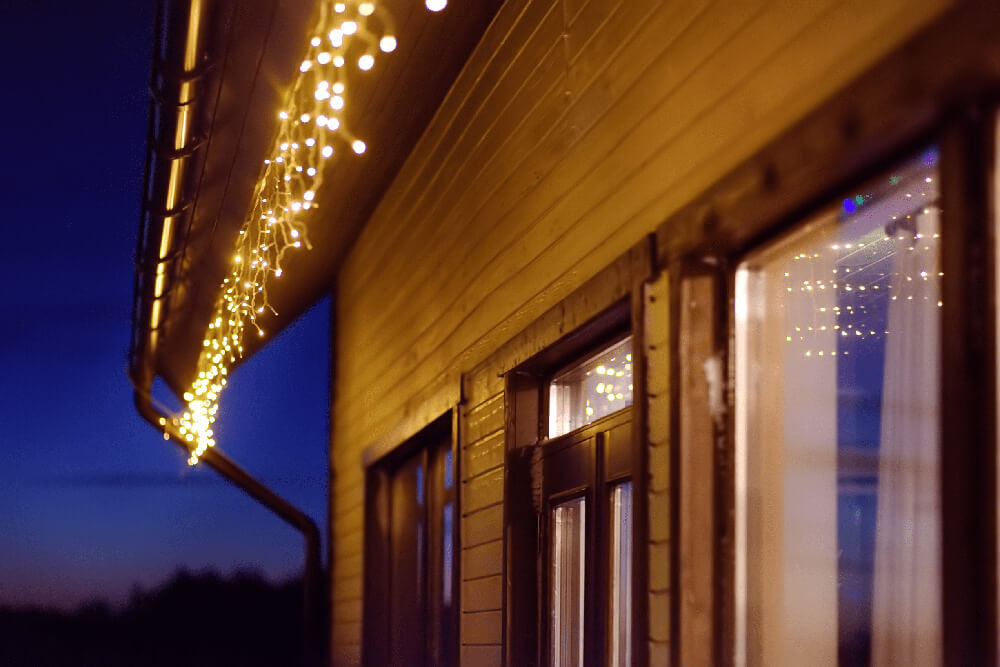 House roofline with string lights at dusk.