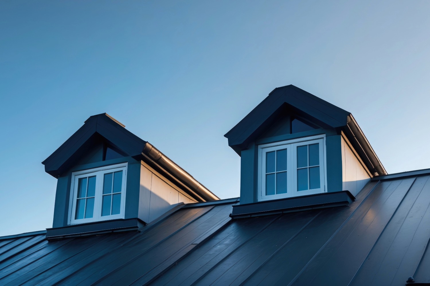 Two dormer windows on a metal roof.