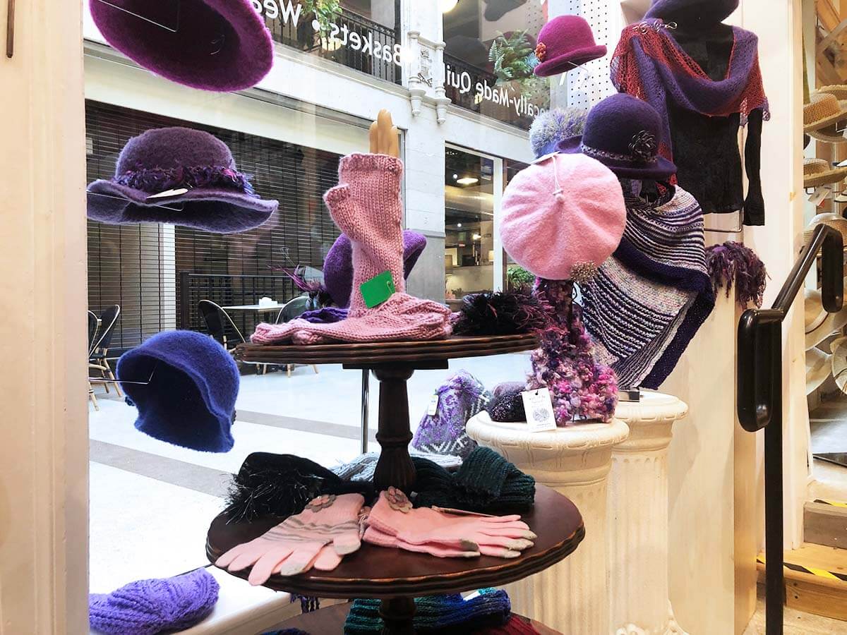 Window display of hats and scarves by local artisans at Asheville Home Crafts