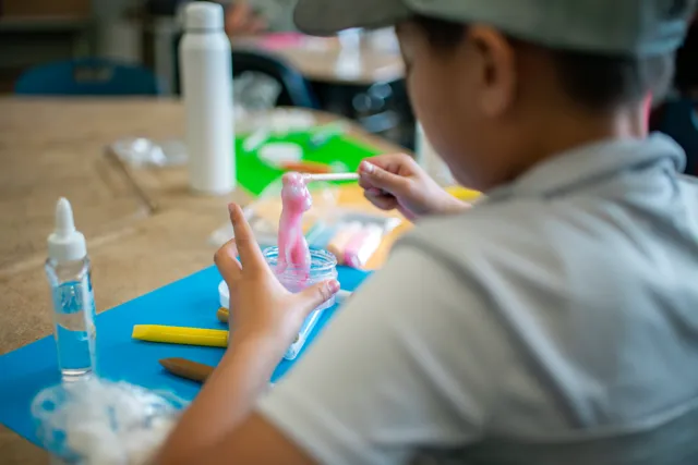 A young boy sitting at a table working on crafts.