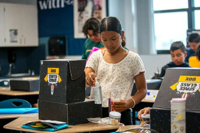 A group of children sitting at desks working on a project.