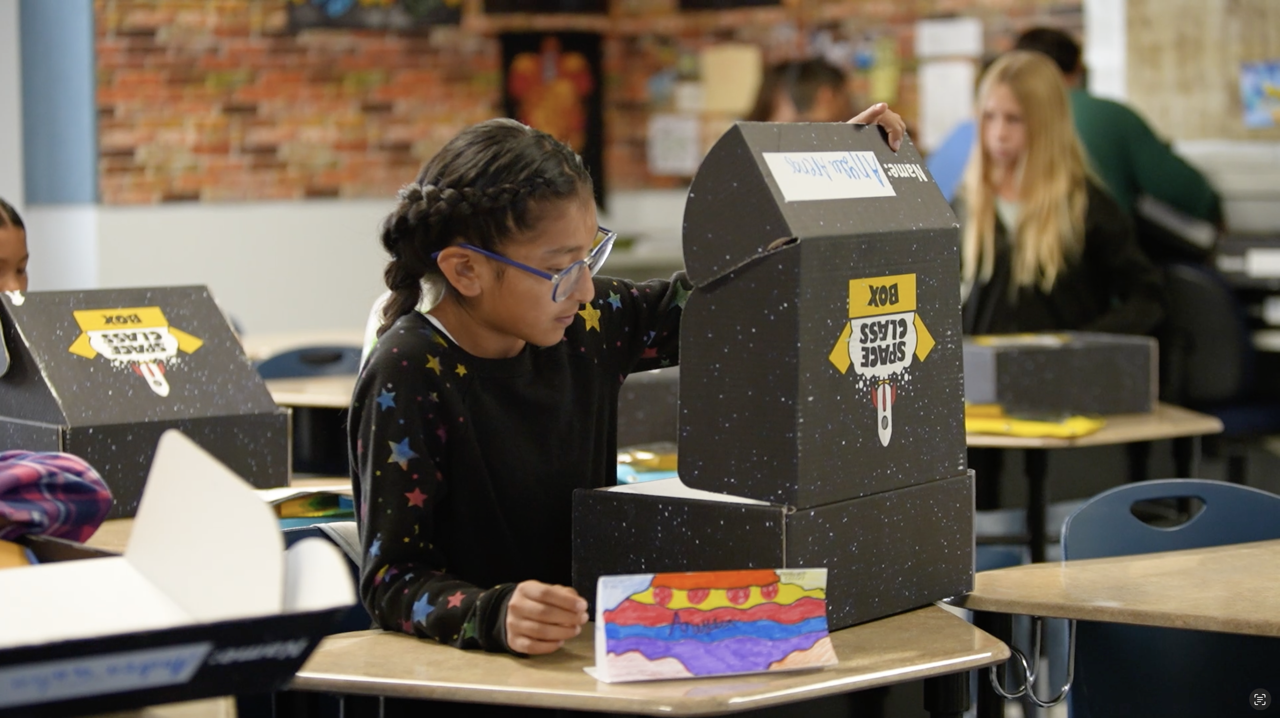 A group of children sitting at desks working on a project.
