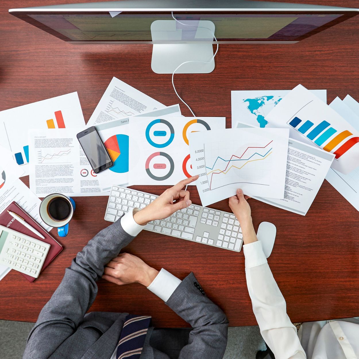 Overhead view of hands reviewing Data Suite marketing performance charts and social listening reports.