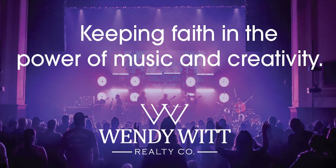 Audience watching a live concert with stage lights and musicians, overlaid with white text that reads 'Keeping faith in the power of music and creativity.' and the Wendy Witt Realty Co. logo.