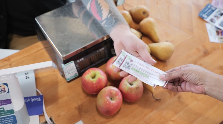 Patient paying for fruits and vegetables with SWPRx Fresh Produce Bucks