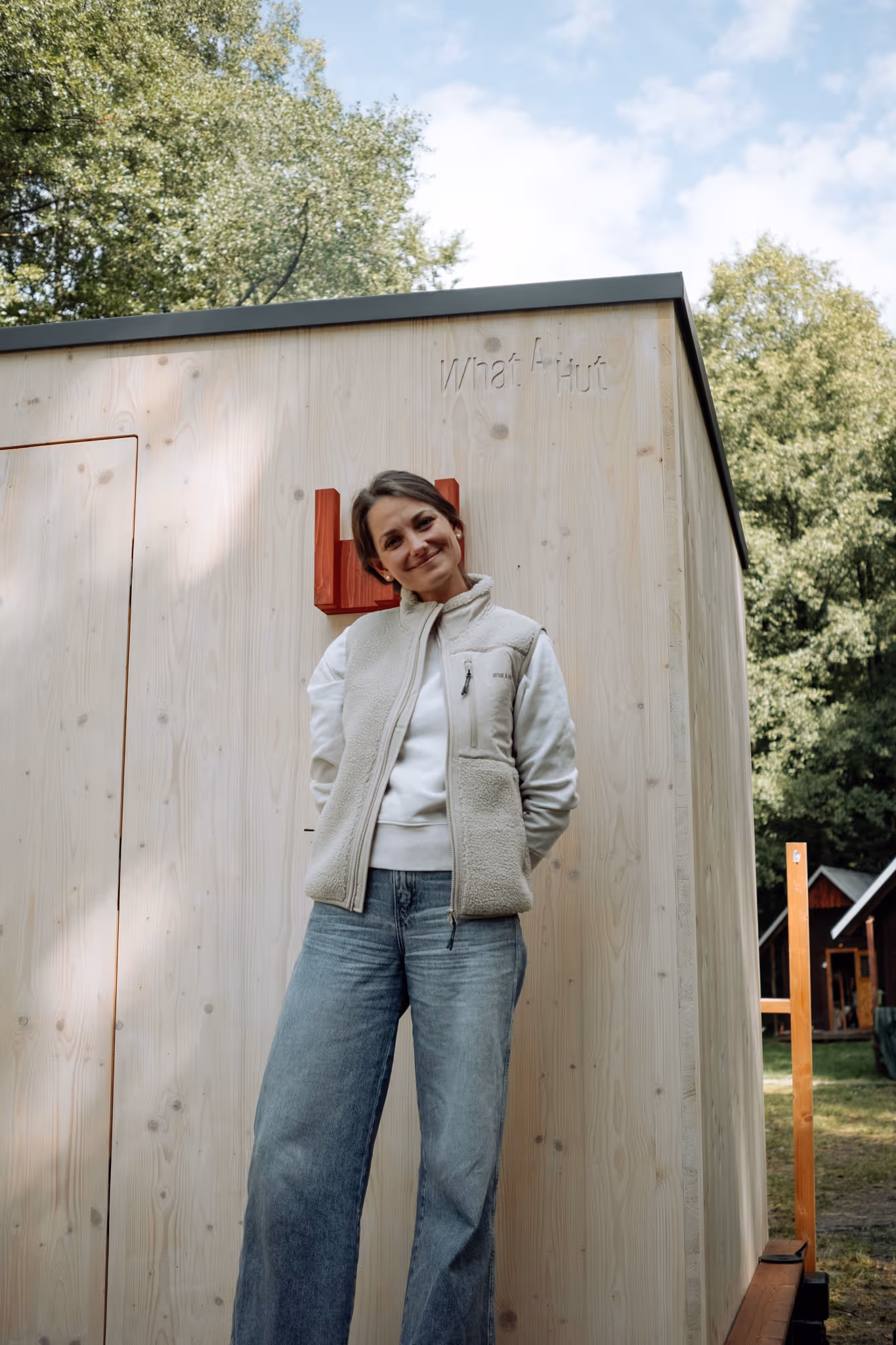 Spoluzakladatelka firmy, Lenka Sršňová, před dřevěnou venkovní saunou s gravírovaným logem What A Hut.