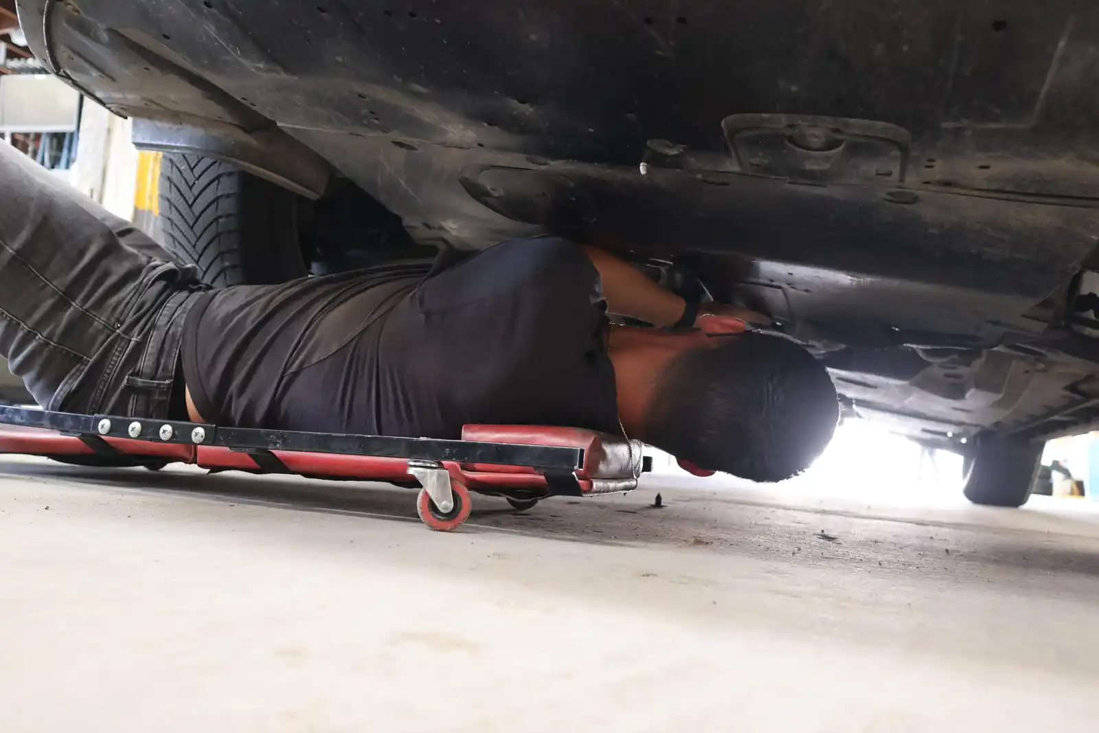 mécanicien allongé sous une voiture en train de la réparer
