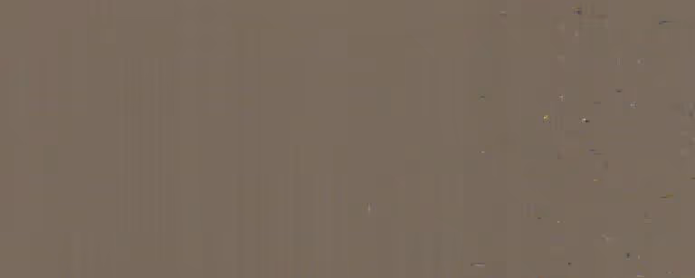 Close-up view of a smooth, solid surface with a muted brown-gray color and scattered small dark specks.