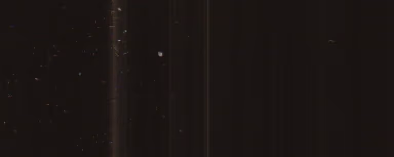 Dark brown metallic surface with vertical lighter streaks and scattered small bright spots.