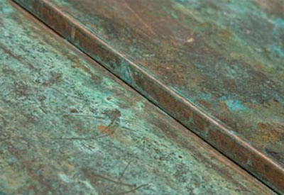 Close-up of weathered greenish-blue copper metal sheets with patina and texture.