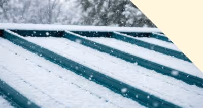 Metal roof covered with fresh snow during a snowfall.