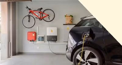 Electric vehicle charging in a modern garage with a red bicycle mounted on the wall and energy equipment installed.