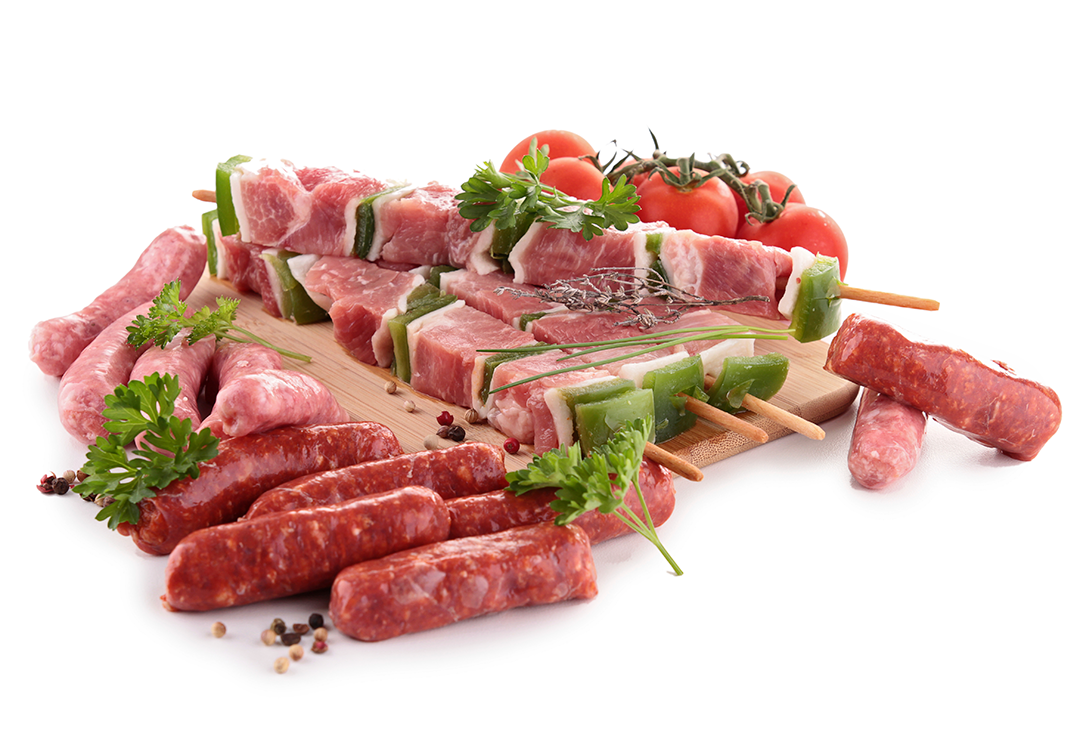 Raw skewers with chunks of pork and green bell peppers on a wooden board, surrounded by sausages, cherry tomatoes, and parsley sprigs.