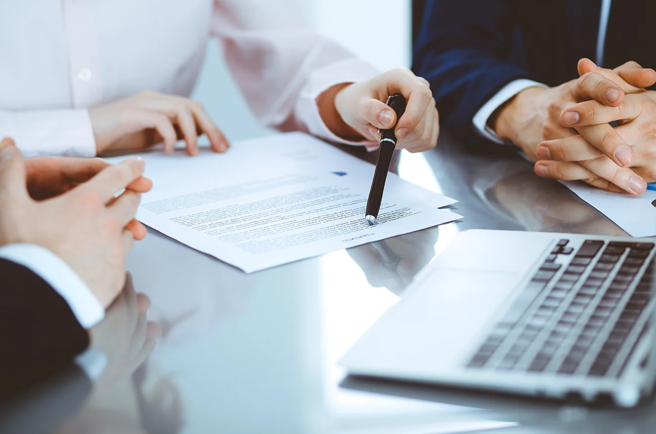 A hand holding a pen to point at a document