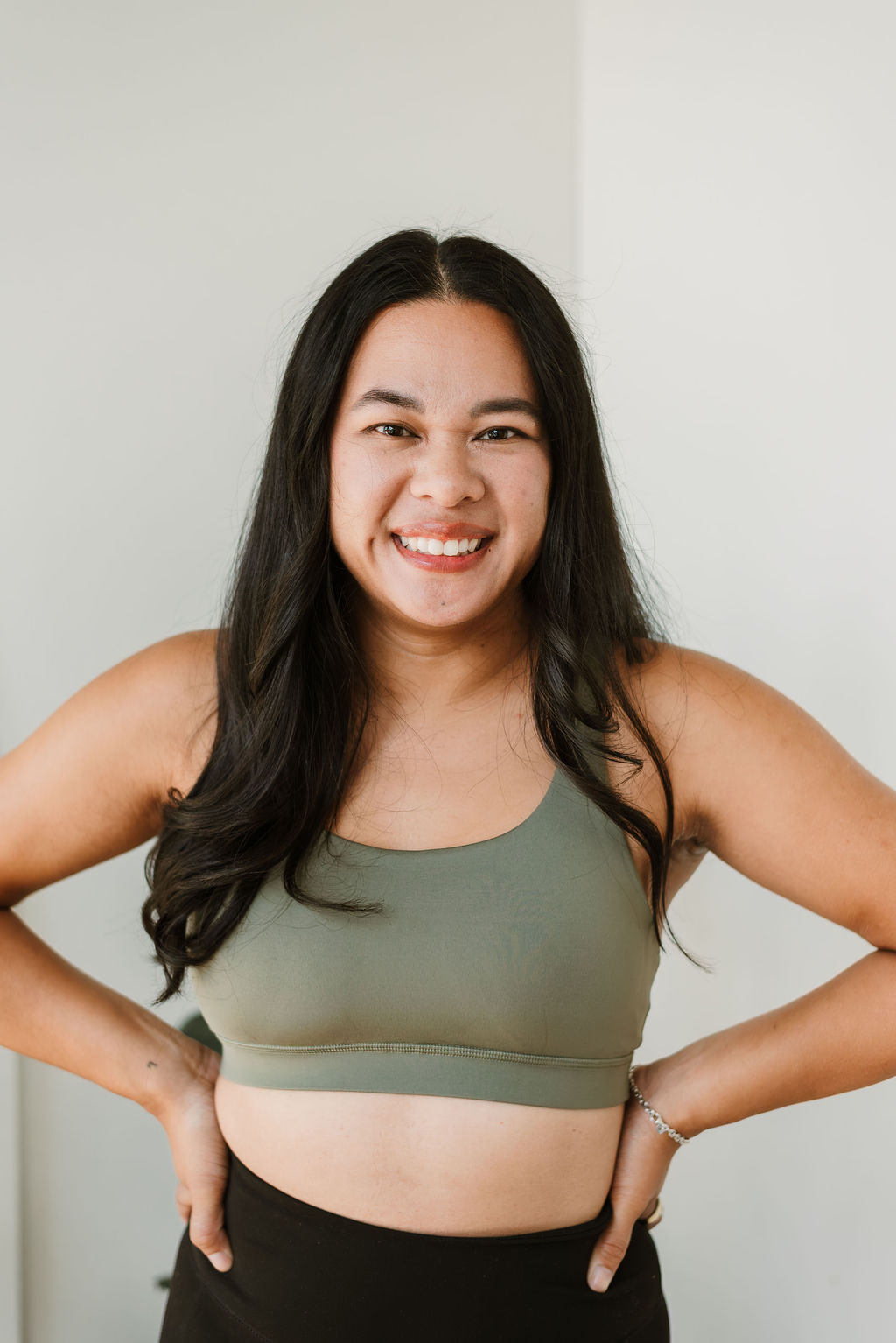 Instructor, Mina, wearing green sports cropped top with both hands on hips.