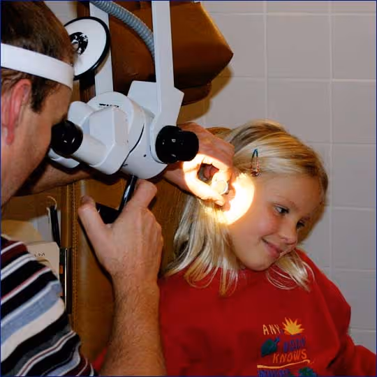 Arzte untersucht Mädchen, ca. 10 Jahre mit dem Otoskop im Ohr