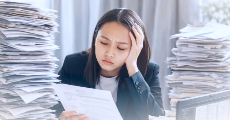 Group of five young professionals smiling and celebrating around a laptop in a modern office.